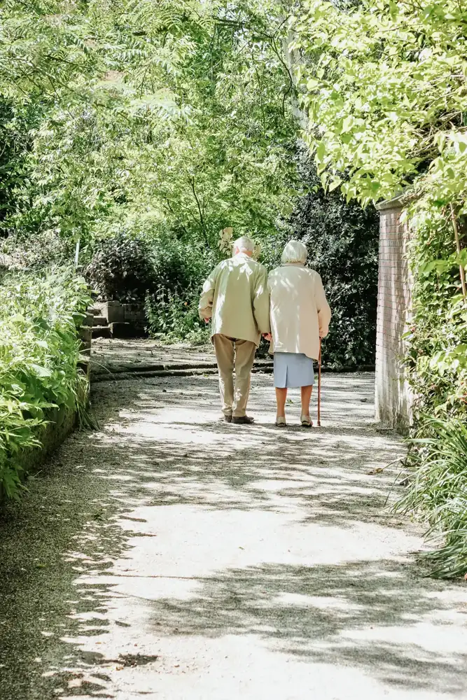 Älteres Paar spaziert auf einem Gartenweg